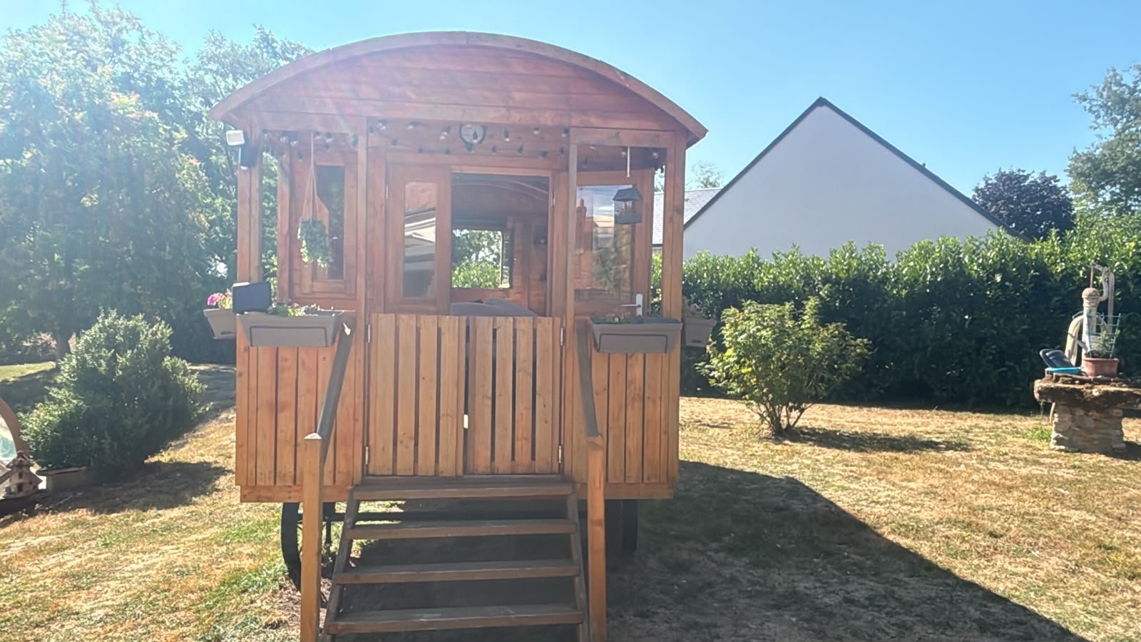 Vue de face de la roulotte en bois installée dans le jardin